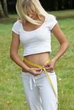 Sporty, young woman measuring waist circumference with a tape 
