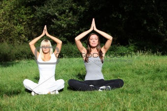 two young women meditate in the nature