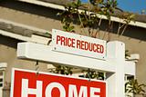 Price Reduced Real Estate Sign in Front of Beautiful New Home.