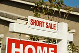 Short Sale Real Estate Sign in Front of Beautiful New Home.