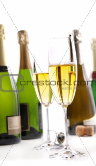 Glasses of champagne with bottles on white