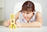 Girl is focused to build a tower with domino on table