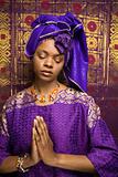 Young African American Woman Praying and Wearing Traditional African Dress