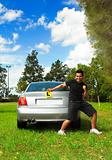 Excited male holding licence permit plates beside silver car