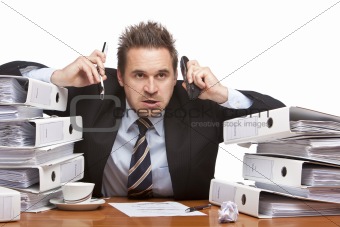 Stressed business man with telephones sitting frustrated between