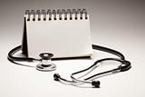 Blank Spiral Note Pad and Black Stethoscope on a Gradated Background.