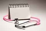 Blank Spiral Note Pad and Pink Pediatric Stethoscope on Gradated Background.