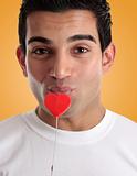 Amorous man kissing love heart on a stick