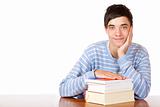 Young happy smiling male student sitting on desk with books