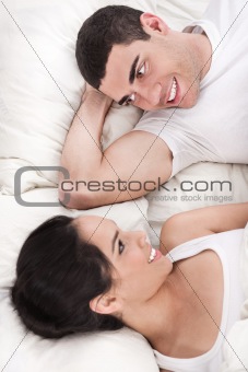 Young smiling romantic couple lying in bed