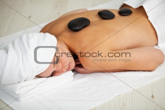pretty young woman in a spa with stones on her back
