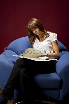 pretty young woman sitting in a chair reading a book