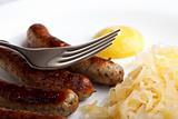 fried sausages,mustard and sauerkraut on a plate with a fork