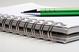 extreme closeup of a ballpoint pen and spiral notebook