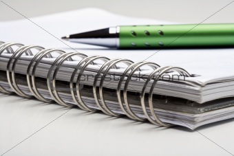 extreme closeup of a ballpoint pen and spiral notebook