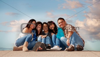 Hispanic family seated against a cloudy sky