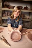 Young girl making bowl in clay studio
