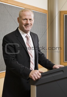 Business Man Standing at Podium Smiling