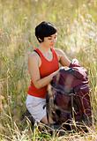 Woman opening backpack in field