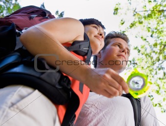 Couple with backpacks looking at compass