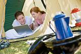 Couple laying in tent with laptop