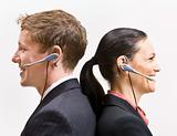 Business people in headsets standing back to back