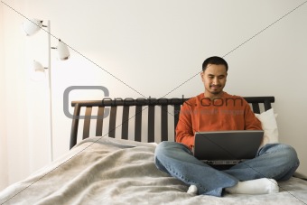 Young Man in Bed Using Laptop