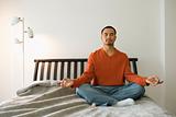 Young Man Meditating in Bedroom