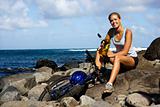 Attractive Young Woman Sitting With Bicycle on Rocky Beach