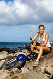 Attractive Young Woman Sitting With Bicycle on Rocky Coast