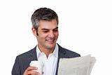 Charismatic businessman drinking a coffee while reading a newspa