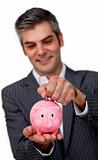 Confident businessman saving money in a piggybank against a white background