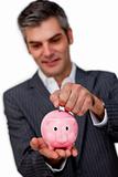 Sophisticated male executive saving money in a piggybank