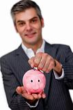 Charismatic male executive saving money in a piggybank