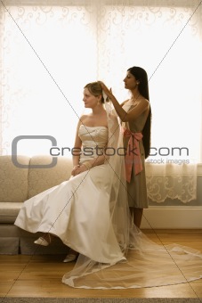 Bridesmaid placing veil.