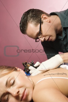 Man tattooing woman.