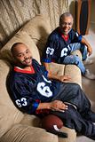 African-American father and son sitting on couch.