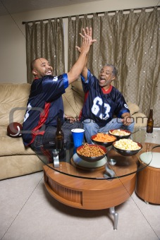 African-American father and son giving high five in living room.