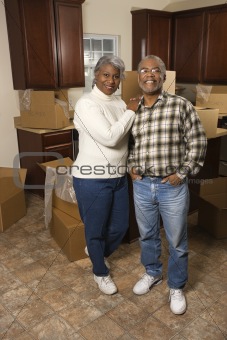 Middle-aged couple standing in kitchen.