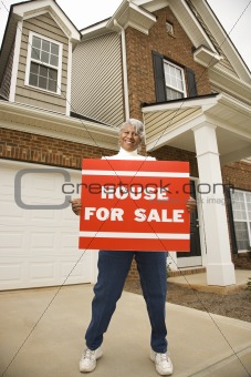 Middle-aged woman holding a for sale sign.