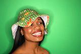 African-American woman wearing green hat on green background.