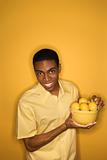 African-American man holding bowl of lemons.