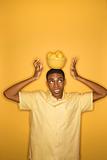 African-American man balancing bowl of lemons on his head.