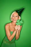 Young Caucasian woman wearing party hat and holding shamrock.