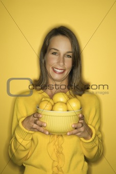 Young Caucasian woman holding bowl of lemons.
