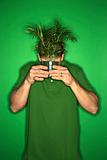 Caucasian man holding plant in front of his face.