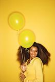 Young African-American woman holding balloons.