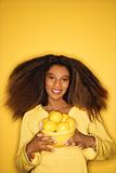 Young African-American woman holding bowl of lemons.