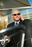 Businessman wearing sunglasses and talking on cellphone.