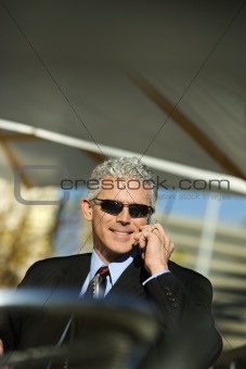 Businessman talking on cellphone outside.